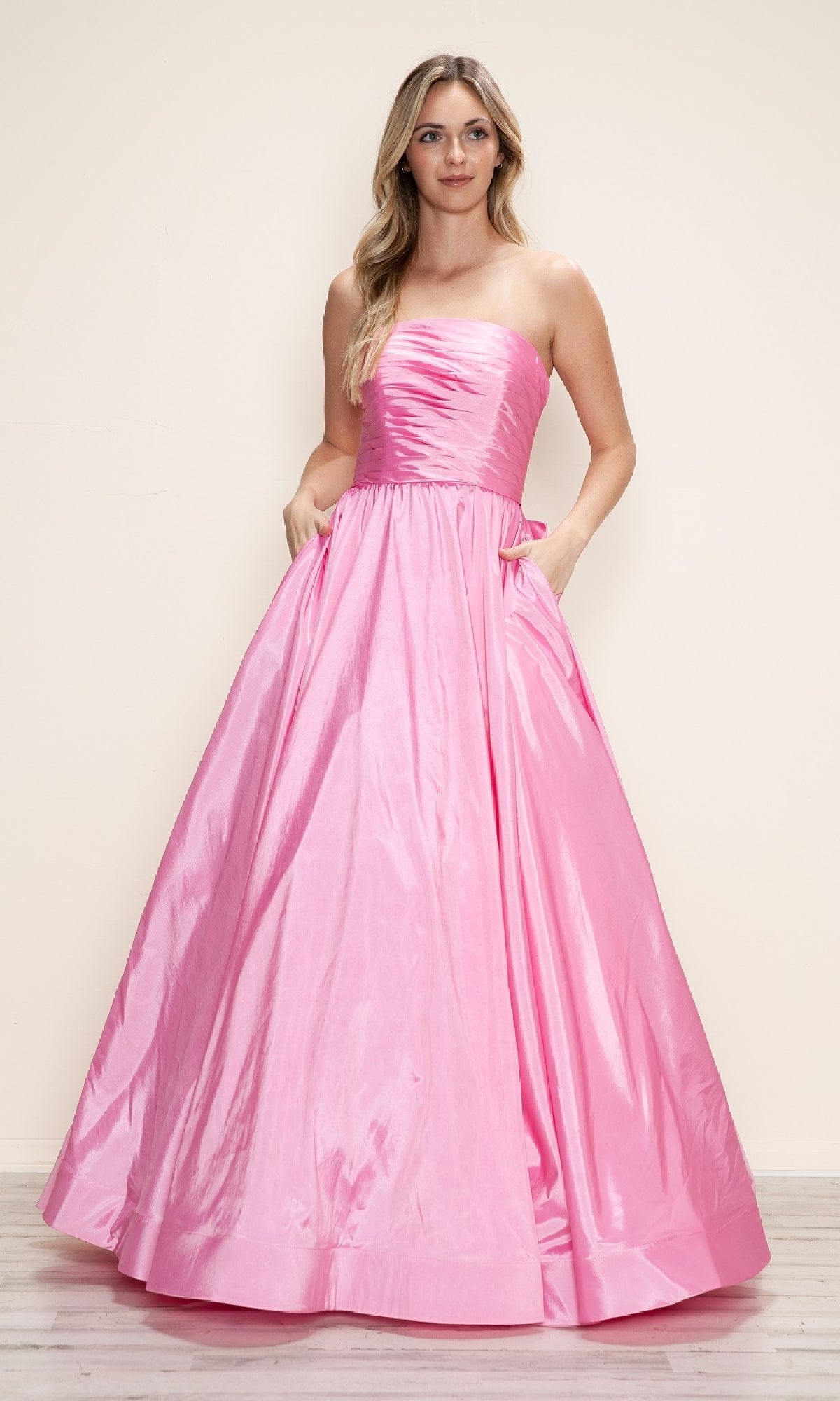 A woman in the Long Prom Dress: Poly USA 9754, a strapless taffeta gown with a ruched bodice, full skirt, and adjustable lace-up back, stands against a plain light background.